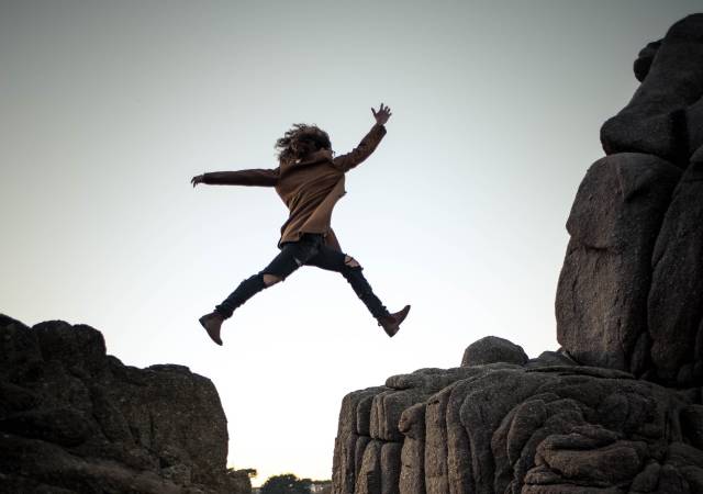 A person jumping in the air over rocks.