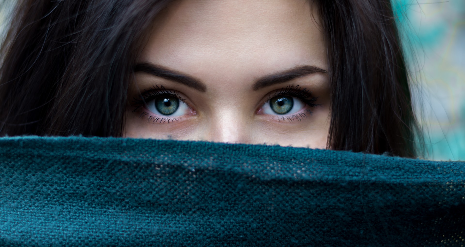 A woman with green eyes peeking over her face.
