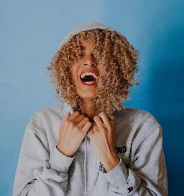 A person with curly hair is holding their head.